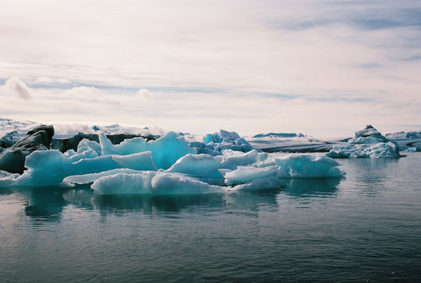 Icebergs floating in a body of water with a cloudy sky.