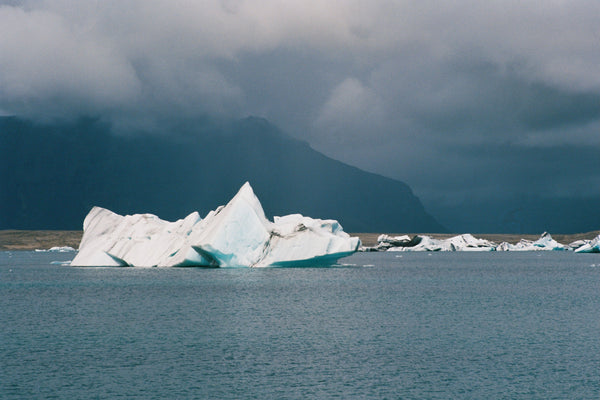 Iceberg floating in a body of water with mountains in the background
