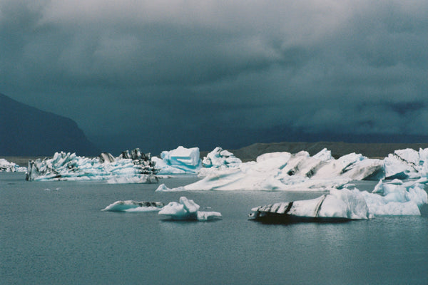 Icebergs floating in a body of water with a dark, stormy sky.