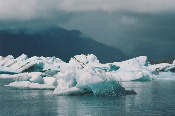 Icebergs floating in water with mountains in the background