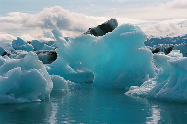 Large ice formations in a body of water with a cloudy sky.